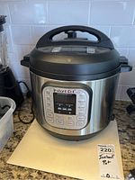 Full view of Instant Pot IP-DUO pressure cooker on kitchen counter with stainless steel body and black lid handle.