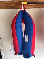 Red and blue pool floatie chair hanging, showing front view with tag attached.