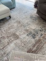 Overall view of the rug placed in living room area with some furniture visible around it showing the pattern and colors.