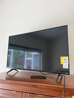 Front view of the Vizio 38 inch smart TV showing the screen, black slim bezel, and legs stand on wooden surface.