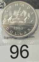 Reverse of the 1963 Canada silver dollar showing the iconic voyageur canoe scene with two men paddling and trees in the background, dated 1963.