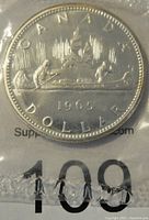 Reverse side of the 1965 Canada silver prooflike dollar coin displaying canoe scene and date.