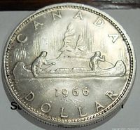 Reverse side of the 1966 Canada silver dollar displaying two men in a canoe.