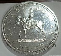 Obverse side of the 1973 Canadian silver dollar coin showing the Royal Canadian Mounted Police officer on horseback with inscription 'CANADA DOLLAR' and '1873-1973'.