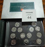 Top view of the coin display showing 16 silver-colored coins in black case with outer box behind