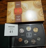Photo showing original gold and brown box labeled '2001 Royal Canadian Mint Specimen Set' with coins arranged in black tray inside.