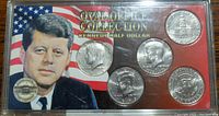 Front side of the display case showing four Kennedy half dollar coins with patriotic background and JFK portrait.