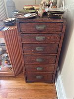 Front view showing six drawers with ornate metal handles and overall wood finish.