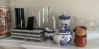 Wide view of shelf showing Blue Willow tea set, crystal vases, and small ceramic pots.