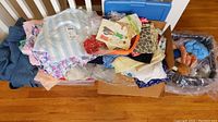 Box of mixed fabric scraps, patterns and trim on hardwood floor
