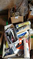 Overview of assorted painting tools in boxes including rollers, paint brushes, trays, and scrapers.