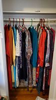 Closet rod with multiple 1980s vintage women’s garments on hangers