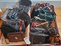 Full view of assortment of leather handbags and purses in various colors and styles in a cardboard box