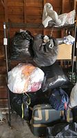 Full view of black metal shelving unit holding multiple filled bags and boxes.