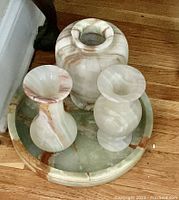 Tray with three onyx vases placed inside, natural banded patterns visible, slight chip on edge of one vase.