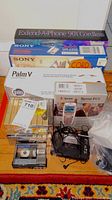 Assorted boxed electronics and audio tapes arranged on floor