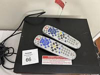 Two Bell satellite receivers stacked with two remote controls on top, power cords visible.