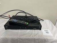 Front view of one Bell satellite receiver with remote on top, showing front panel with buttons and card slot.