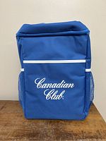 Front view of blue cooler backpack with Canadian Club logo on front panel showing color and design