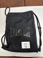 Front view of black Everlast drawstring bag showing the Everlast logo and zippered front pocket.