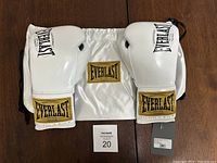 Pair of metallic white Everlast boxing gloves with black logos, lace-up wrists, and original tags attached. Gloves placed facing each other with the Wald text visible on the wrist area.