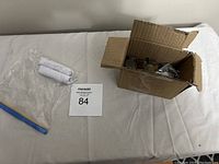 Wide shot of the cardboard box filled with coins and the ziplock bag containing rolled coins beside the auction card.