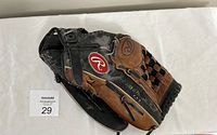 Rawlings baseball glove laid flat showing front with worn black and brown leather and red Rawlings logo on wrist strap.