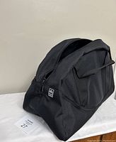 Front angle view of the black Stormtech travel bag showing the side zipper, shape, and shoulder strap.