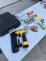 DeWalt carrying case, staple gun, and assorted staple packs displayed on white table.
