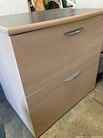 Front view of the wooden 2-drawer filing cabinet with light wood grain finish and metal handles.
