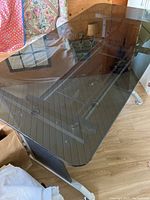 Photo showing angled view of the tinted glass desk top and metallic frame and legs.