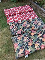 Photo of four different patio chair cushions laid on grass, showing color patterns and relative condition.