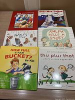Six children's picture books spread on a table showing front covers including titles and illustrations.