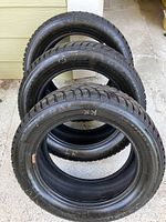 Three used Altima Arctic snow tires stacked showing sidewalls and tread view.