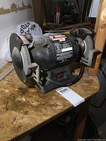 Front view of the bench grinder showing brand label, power switch, and dual grinding wheels.