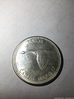 Reverse side of the coin showing a flying Canada goose with 'CANADA 1867-1967' and 'DOLLAR' inscriptions, silver with light wear.
