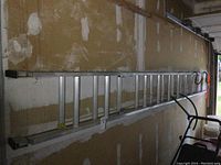 Full view of the aluminum extension ladder mounted on garage wall, showing length and structure.
