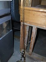 Two fishing rods leaning against a wooden surface beside a refrigerator.