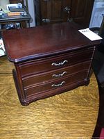Closed view of large wooden jewelry box with dark polished finish and silver-tone drawer handles.