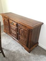 Front view of solid wood vintage buffet cabinet showing two side doors, central drawer and cabinet door, and wood grain finish.