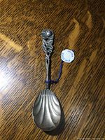 Full view of vintage silver spoon with floral design handle and shell-shaped bowl. Tag attached showing 'ECHT SILBER 800/000'.