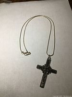 Full view of the 22 inch silver chain laid flat showing clasp and cross pendant