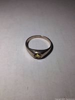 Front side view of sterling silver ring with yellow stone on a white surface