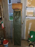 Full front view of the wooden toboggan with vinyl pad, showing its length and front door background setting.