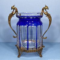 Front view of vase showing blue and clear glass with brass dragon handles and base