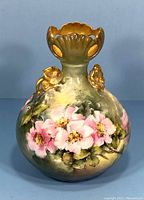 Front view of antique Limoges vase showing pink floral hand paint and gold scalloped rim.