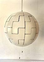 Front view of fully closed white panels pendant light showing spherical shape and pull string.