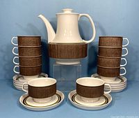Full set arranged with coffee pot elevated in center, cups stacked on saucers on either side