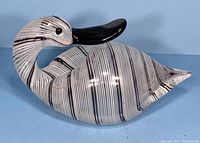 Profile view of duck figurine showing body shape and stripe pattern