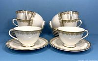 Front and side view of eight Royal Doulton teacups and saucers arranged in two stacks against a blue background.